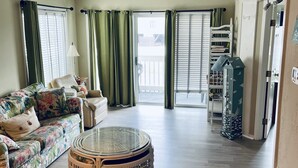 A spacious living room with a sofa, round coffee table, and a dining area with chairs and a table. - A Place at the Beach resort Family Fun!150'Waterslide, indoor pool&Putt Putt (Atlantic Beach)