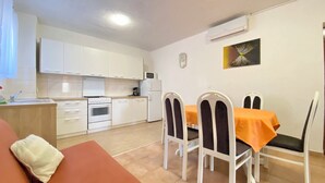 Um espaço compacto com cozinha compacta, área de refeições com mesa e cadeiras, e um sofá.