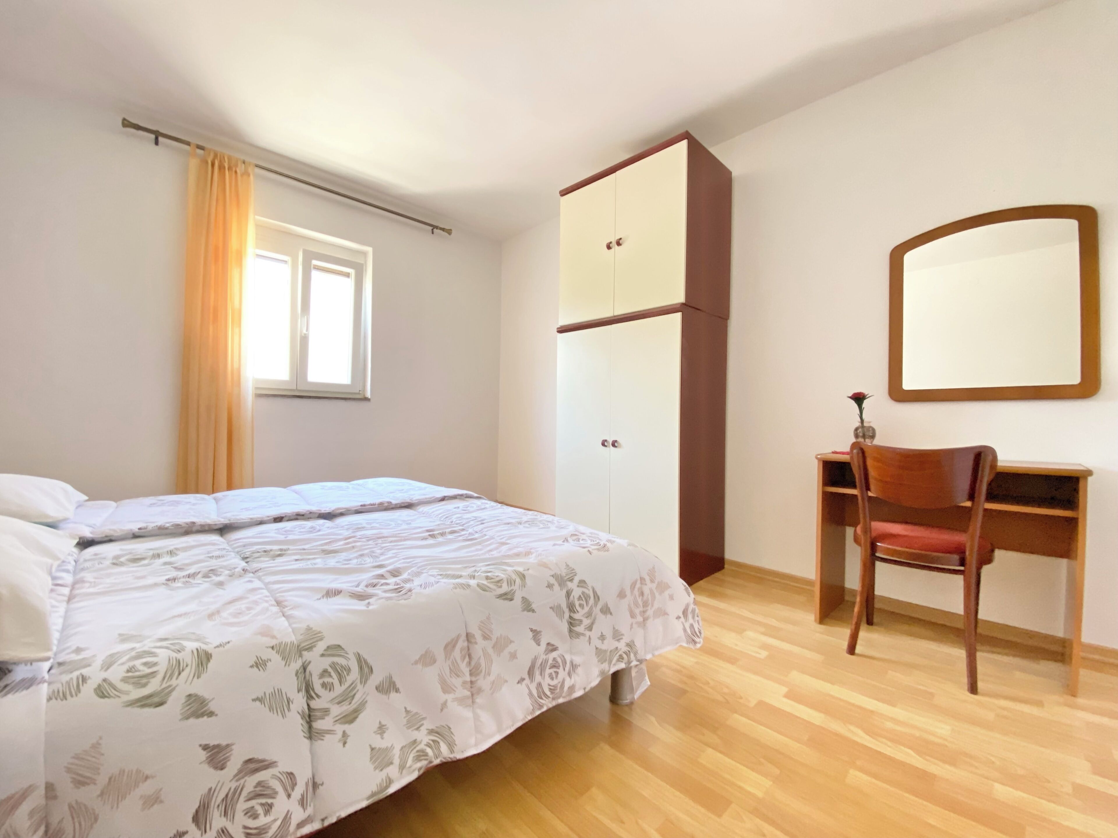 Ein Schlafzimmer mit einem Bett, einem Kleiderschrank, einem Schreibtisch und einem Stuhl.