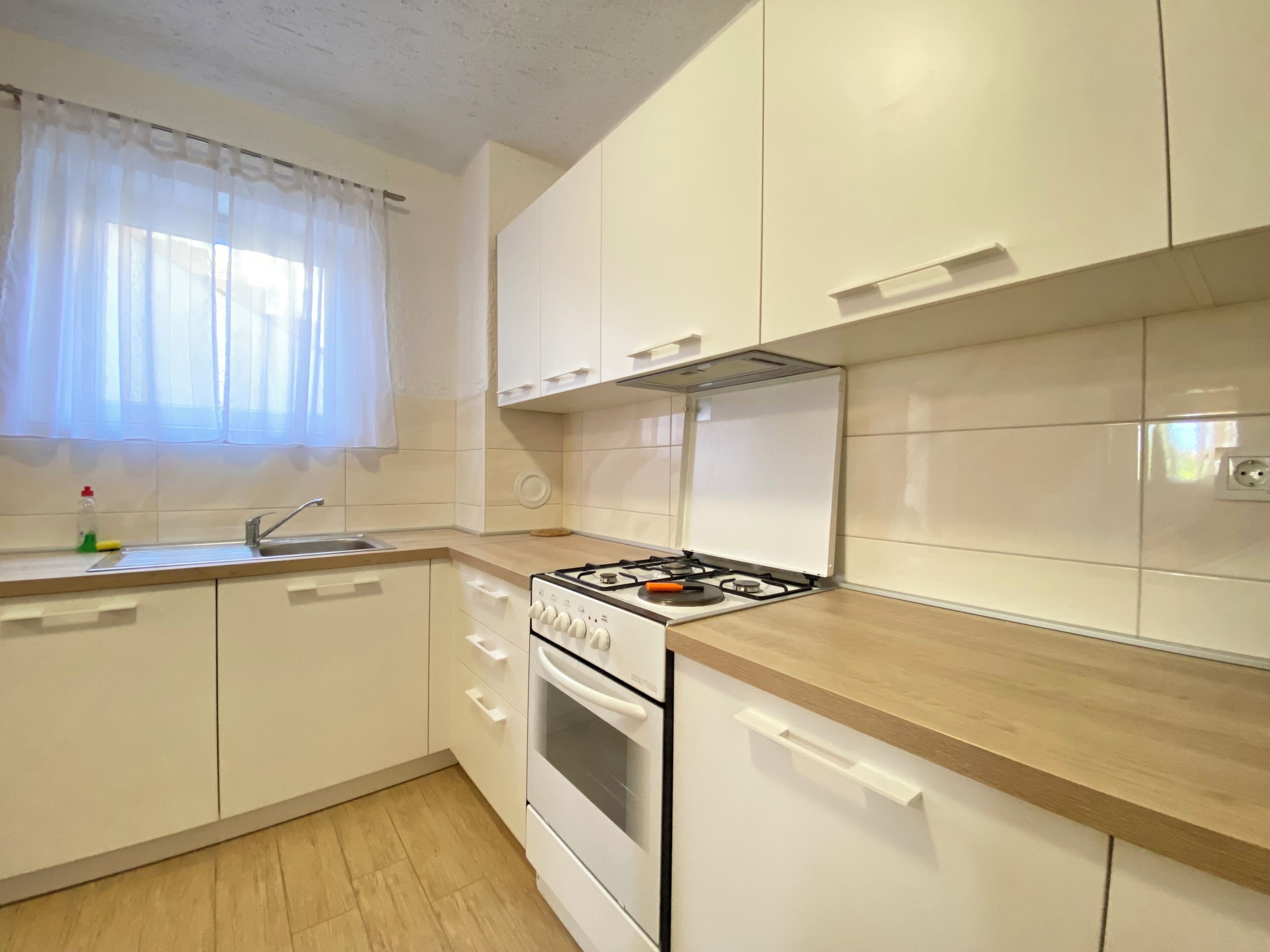 Une cuisine moderne avec des armoires blanches, une cuisinière et un évier.