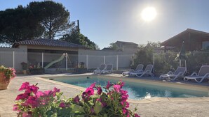 A swimming pool with lounge chairs and a potted plant with pink flowers. - Lovely chalet in Ruoms, pool, Via Ardèche, air-conditioned, 10 min from Vallon (Ruoms)