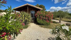 A wooden cabin with a gravel path leading to it, surrounded by lush greenery and flowering plants. - Lovely chalet in Ruoms, pool, Via Ardèche, air-conditioned, 10 min from Vallon (Ruoms)