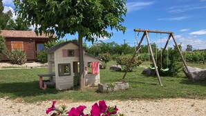 A playhouse with a small bench, a swing set, and a garden with pink flowers. - Lovely chalet in Ruoms, pool, Via Ardèche, air-conditioned, 10 min from Vallon (Ruoms)