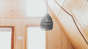 A cozy attic room with wooden walls, a dining table set for four, and a hanging light fixture. - The Fox A-Frame | An Intimate Mountain Retreat (Blue River)