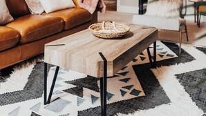 A cozy loft-style living room with a wooden ceiling, a brown leather sofa, a wooden coffee table, and a black spiral staircase. - The Fox A-Frame | An Intimate Mountain Retreat (Blue River)