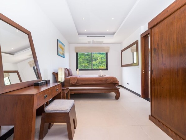 Un dormitorio con cama, cómoda de madera, banca y armario.