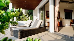 A modern outdoor seating area with wicker furniture and a view of the garden.