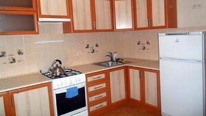A compact kitchen with wooden cabinets, a white refrigerator, and a gas stove.