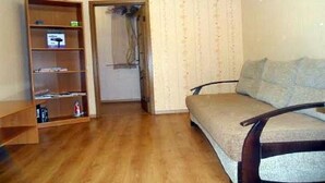 A room with a wooden bookshelf, a sofa, and a door leading to another room.