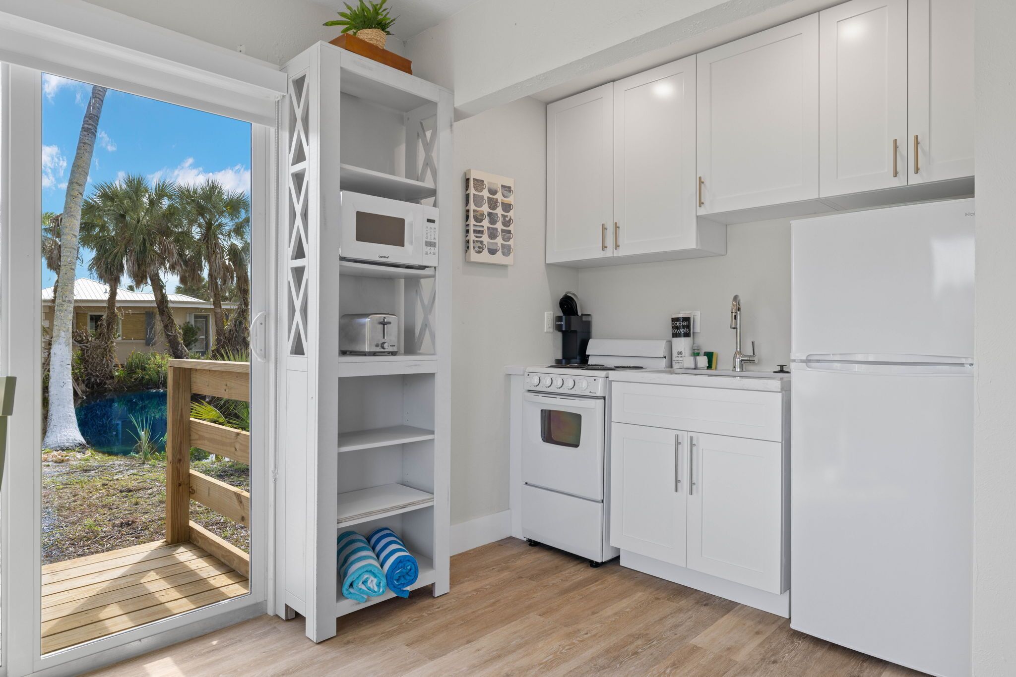 A modern kitchen with white cabinets, a built-in oven, microwave, and refrigerator.