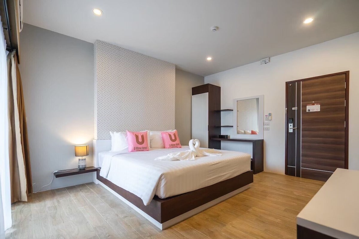 Una habitación de hotel moderna con una cama grande, una mesita de noche y un armario.