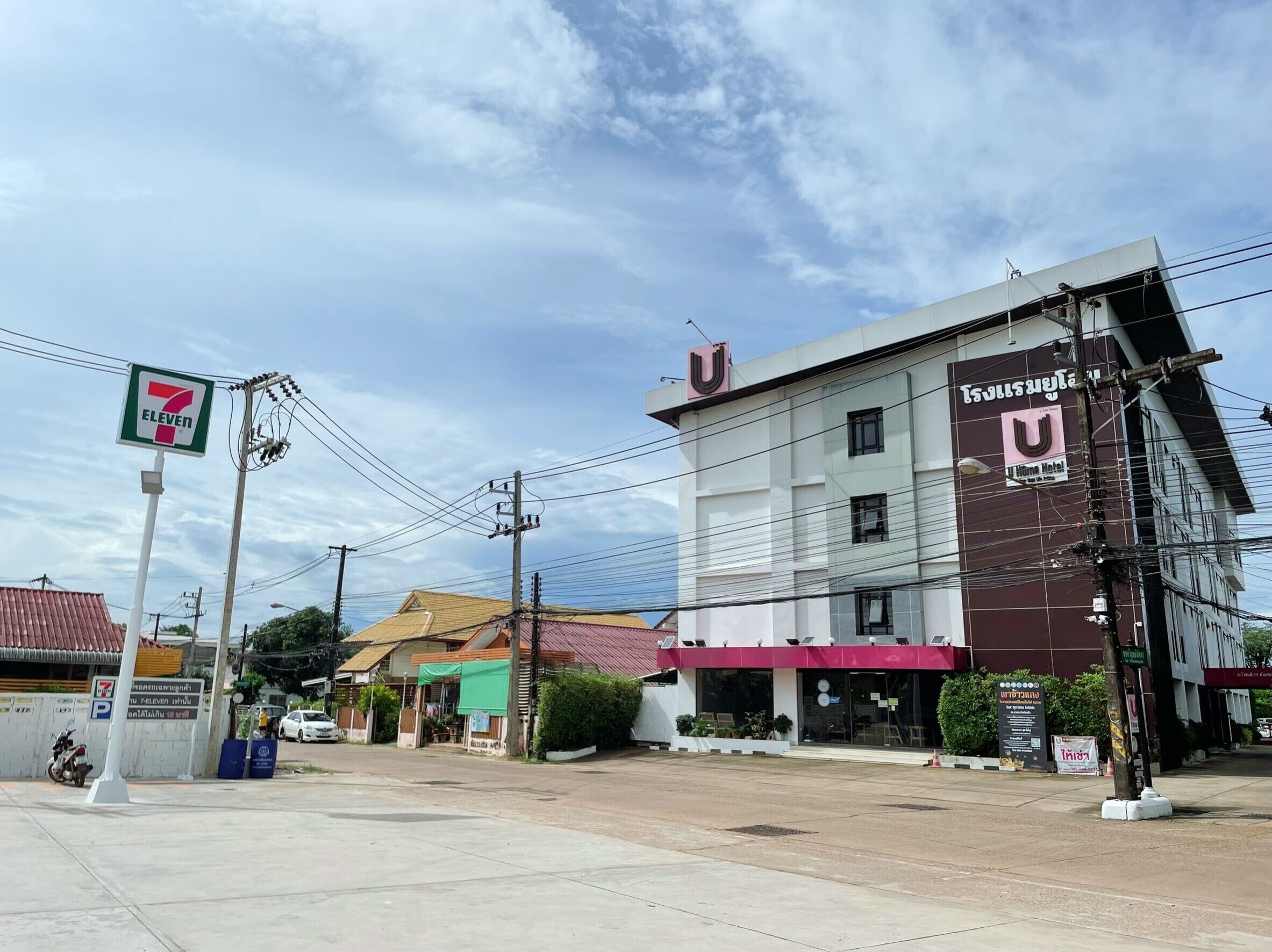 Un hotel con un llamativo letrero en forma de U, una tienda de conveniencia 7-Eleven y un área de estacionamiento.