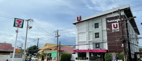 Un hotel con un llamativo letrero en forma de U, una tienda de conveniencia 7-Eleven y un área de estacionamiento.