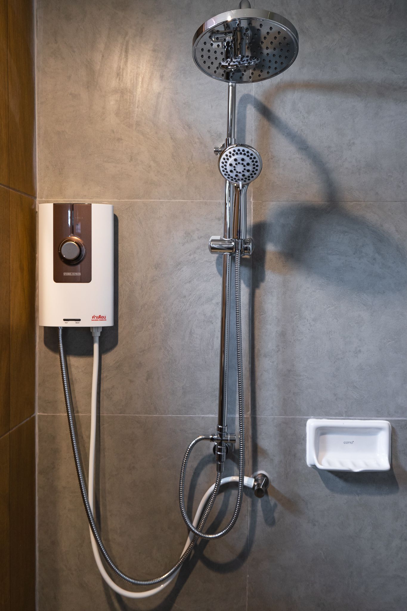 A modern shower with a control panel, a handheld showerhead, and a handheld shower attachment.