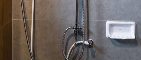 A modern shower with a control panel, a handheld showerhead, and a handheld shower attachment.