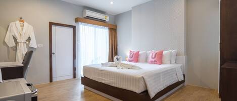 Una habitación de hotel moderna con una cama grande, un escritorio con una silla y un equipo de aire acondicionado.
