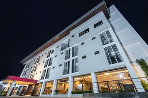 Un hotel de varios pisos con un diseño moderno, con ventanas amplias y una entrada bien iluminada.
