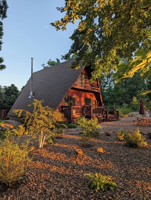 A cabin with a sloped roof, wooden deck, and a chimney. - Cabin Home in the City! (Eau Claire)