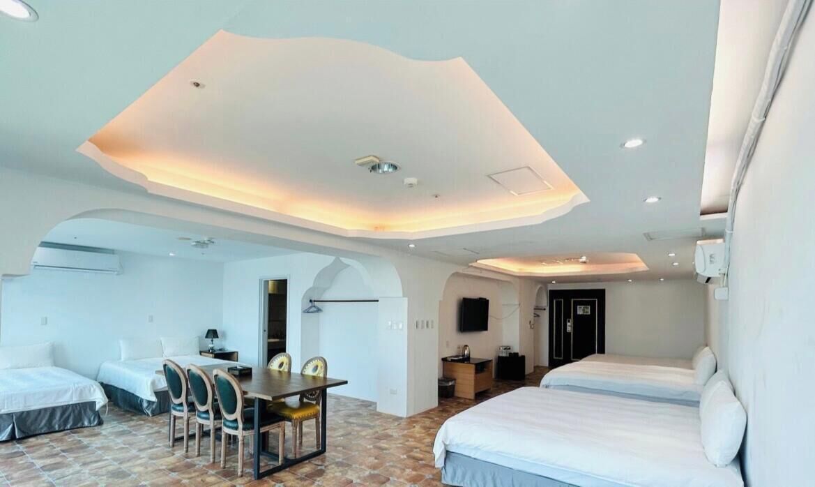A hotel room with a modern design, featuring a large bed, a desk, and a dining area.