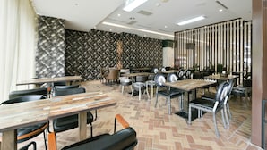 A restaurant with multiple tables and chairs, a patterned wall, and a herringbone floor pattern.