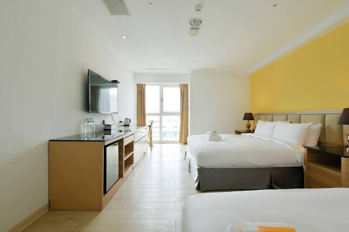 Una habitación de hotel con cama, escritorio, silla, televisión y ventana.