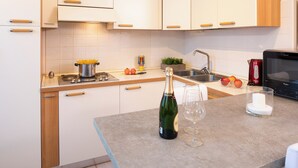 A modern kitchen with white cabinets, a stainless steel sink, and a microwave. - Casa Davide-Apartment in Bardolino (Bardolino)
