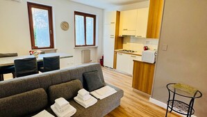 A modern living room with a sofa, a dining table, and a kitchen area. - Casa Davide-Apartment in Bardolino (Bardolino)