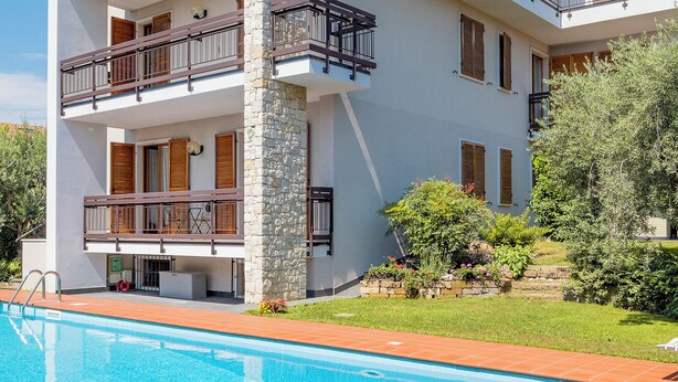 A modern multi-story building with a swimming pool, balconies, and a stone pillar. - Casa Davide-Apartment in Bardolino (Bardolino)
