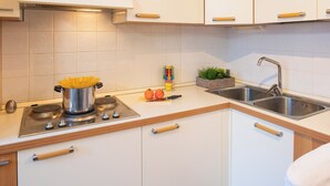 A modern kitchen with white cabinets, a stainless steel sink, and a gas stove. - Casa Davide-Apartment in Bardolino (Bardolino)