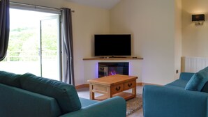 Ein Wohnzimmer mit Flachbildfernseher, Kamin und zwei Sofas.