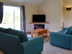 Ein Wohnzimmer mit Flachbildfernseher, Kamin und zwei Sofas.