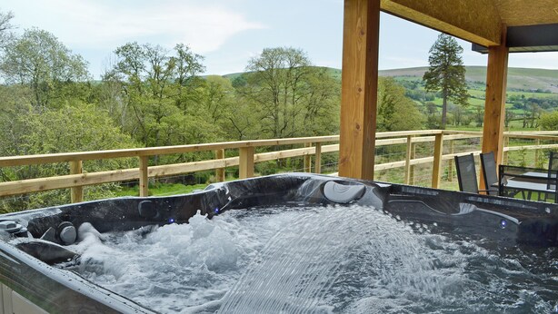 Ein Whirlpool mit einer Holzterrasse und Blick auf eine grüne Landschaft.