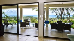 Ein Zimmer mit einer Schiebetür zu einem Balkon mit Sitzgelegenheiten und Blick aufs Meer.