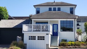 Una casa de dos pisos con una puerta azul y un garaje blanco.