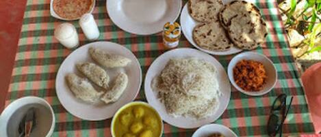 A table with various dishes including rice, bread, and a bowl of yellow fruit.