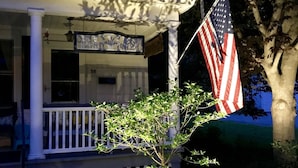 Een huis met een veranda, een Amerikaanse vlag en een boom.