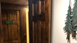 Een nooduitgang met een bordje, een houten vloer en een toiletrolhouder aan de muur met een decoratief object.
