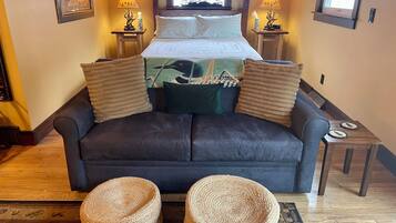 Une chambre à coucher comprenant un lit, deux tables de chevet, deux lampes, une fenêtre et deux poufs en osier.