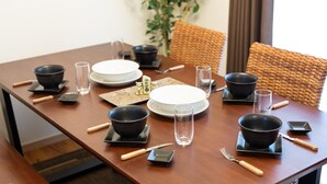 A dining table set with black bowls, plates, glasses, and cutlery. - Pine House in ISHIGAKI (Ishigaki)