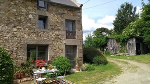 A stone building with a garden and a table set up outside. - Charming stone cottage completely renovated in 2019 (Pleslin-Trigavou)
