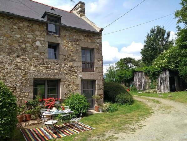 A stone building with a garden and a table set up outside. - Charming stone cottage completely renovated in 2019 (Pleslin-Trigavou)