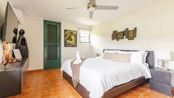 A hotel room with a bed, a desk, a green door, and artwork on the walls.