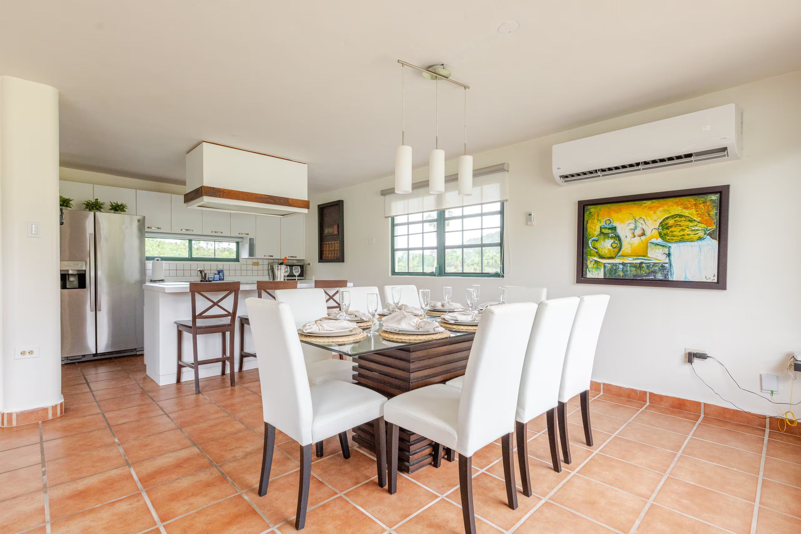 Una cocina moderna con comedor, ventanas amplias y un cuadro en la pared.