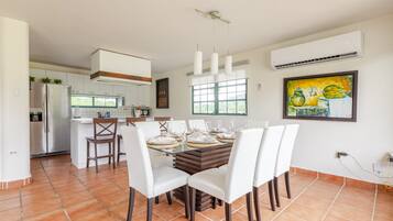 Una cocina moderna con comedor, ventanas amplias y un cuadro en la pared.