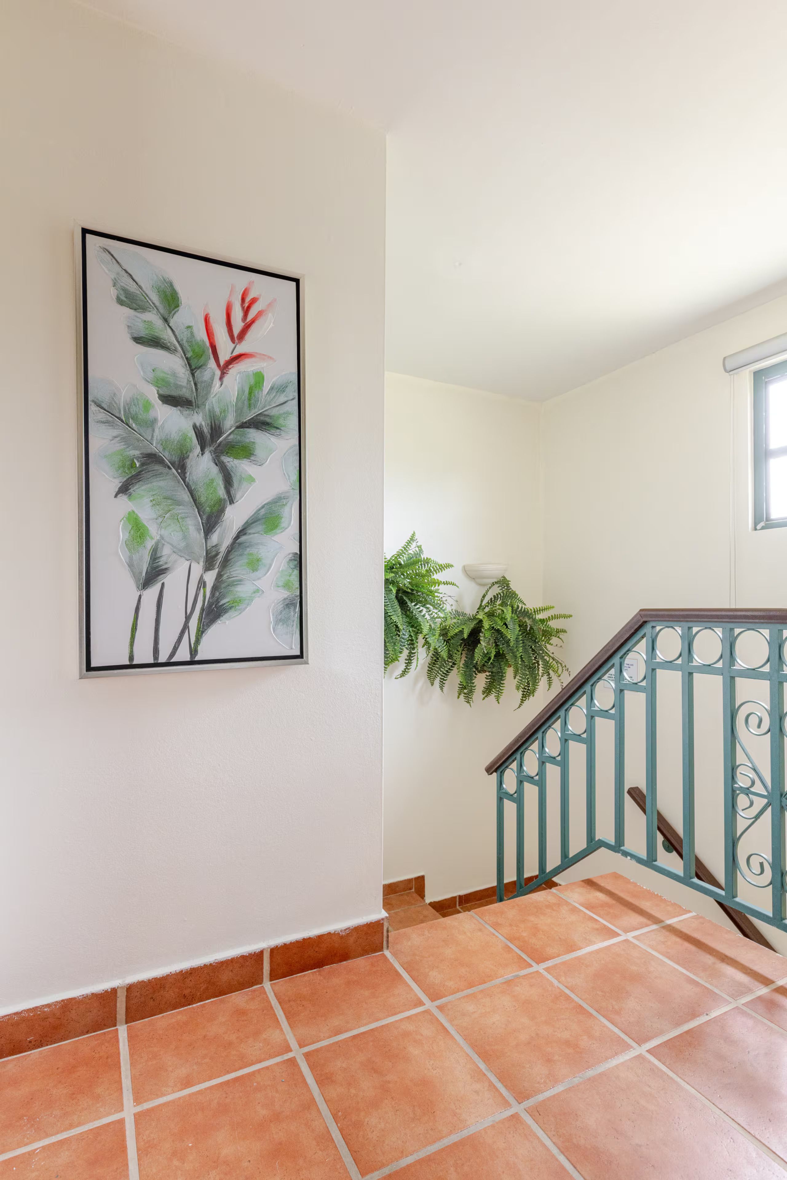 A staircase with a handrail and a wall-mounted plant.