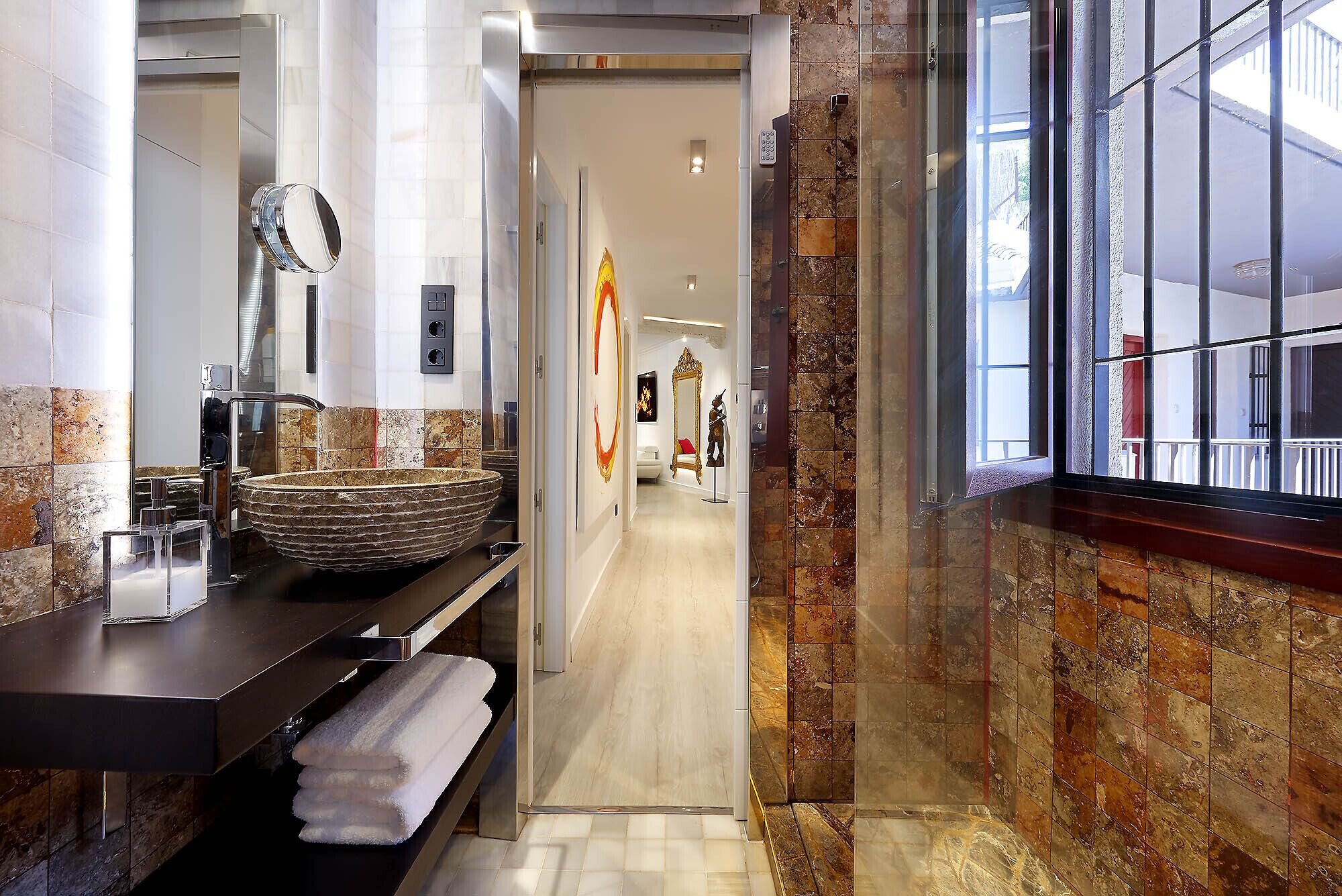 A modern bathroom with a large, round vessel sink, a mirror, and a towel rack.
