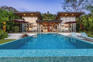 A modern house with a swimming pool, two glass-enclosed rooms, and a patio with lounge chairs. - Vista Azul-Charming Villa with Splendid Ocean Views,Gated Community,Private Pool (Savegre)