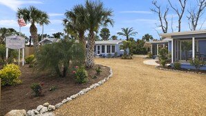 A gravel driveway leading to a row of mobile homes with a sign for Periwinkle Cottages. - Gorgeous Newly Renovated Coastal Cottage "Egret" Minutes to the beach and free bikes!! JULY SAVINGS! (Sanibel)