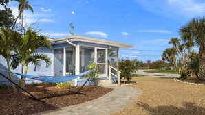 A small house with a porch, a hammock, and a stop sign in the background. - Gorgeous Newly Renovated Coastal Cottage "Egret" Minutes to the beach and free bikes!! JULY SAVINGS! (Sanibel)