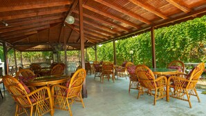 An outdoor covered patio with wicker furniture and a glass table. - Bellissima Hotel (Manavgat)